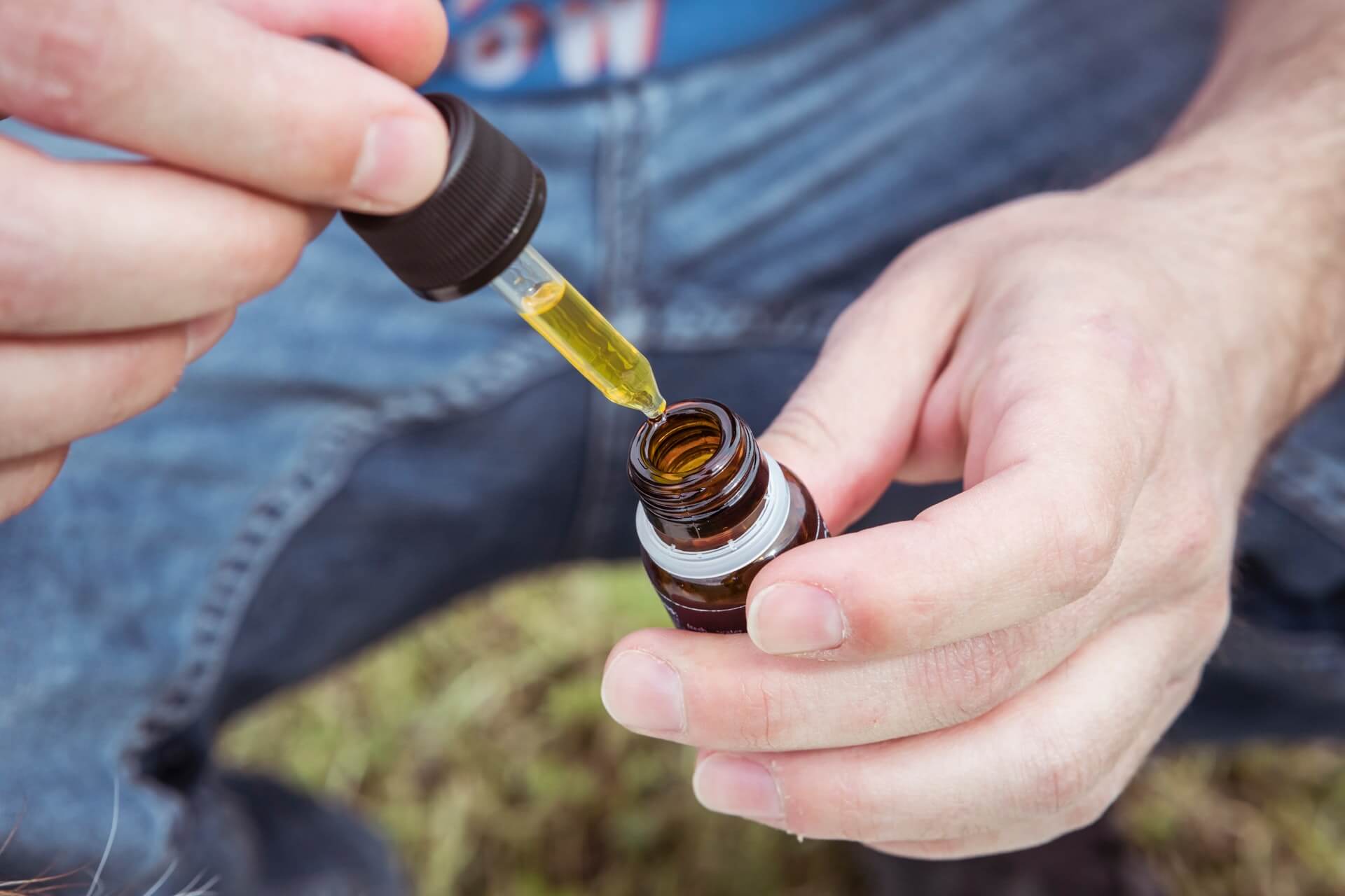 Man holding a full dropper over the bottle